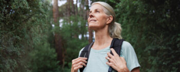 Eine Frau, die im Wald spazieren geht und den Geräuschen lauscht.