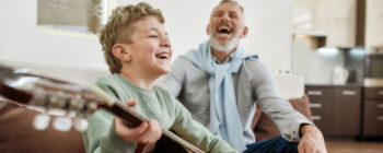 Ein lachender Junge spielt auf einer Gitarre