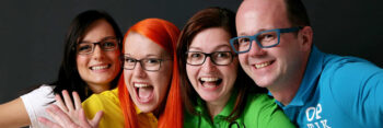 Teamfoto Optik Mayer - 4 Personen lachen in die Kamera